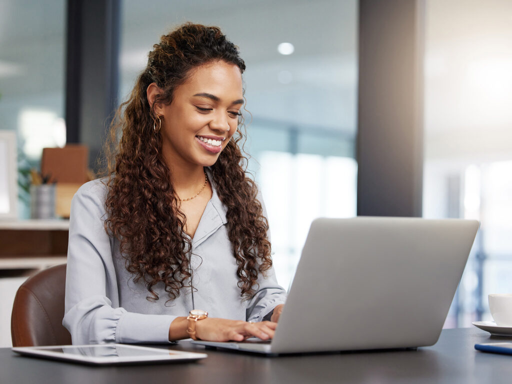 Woman smiling while working on her laptop