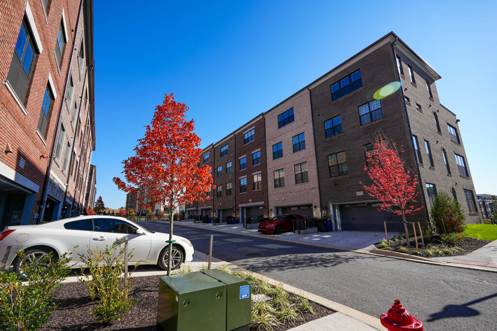 Row of townhouses with car and tree in foreground.