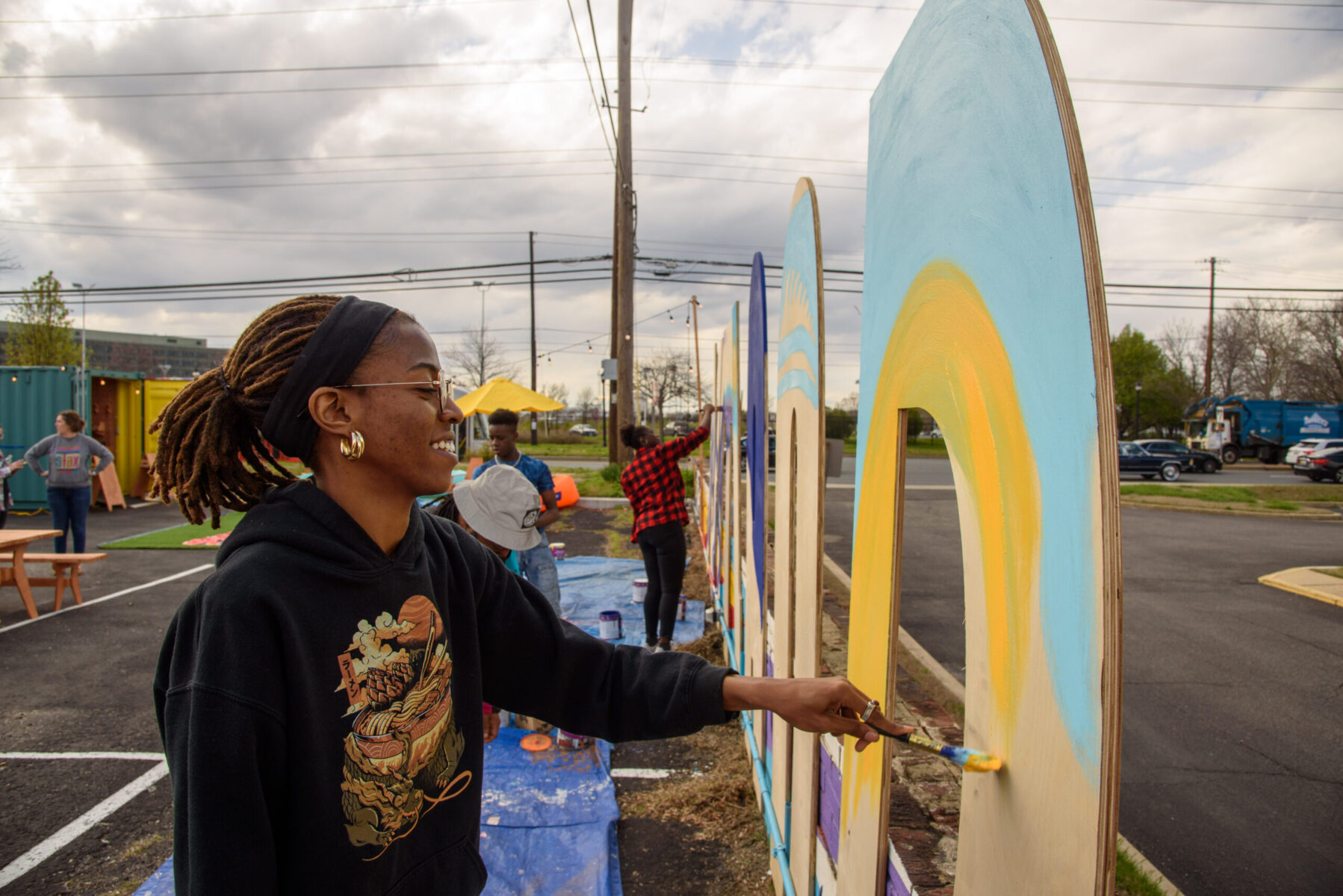 Black woman happily painting mural on SUITland letters