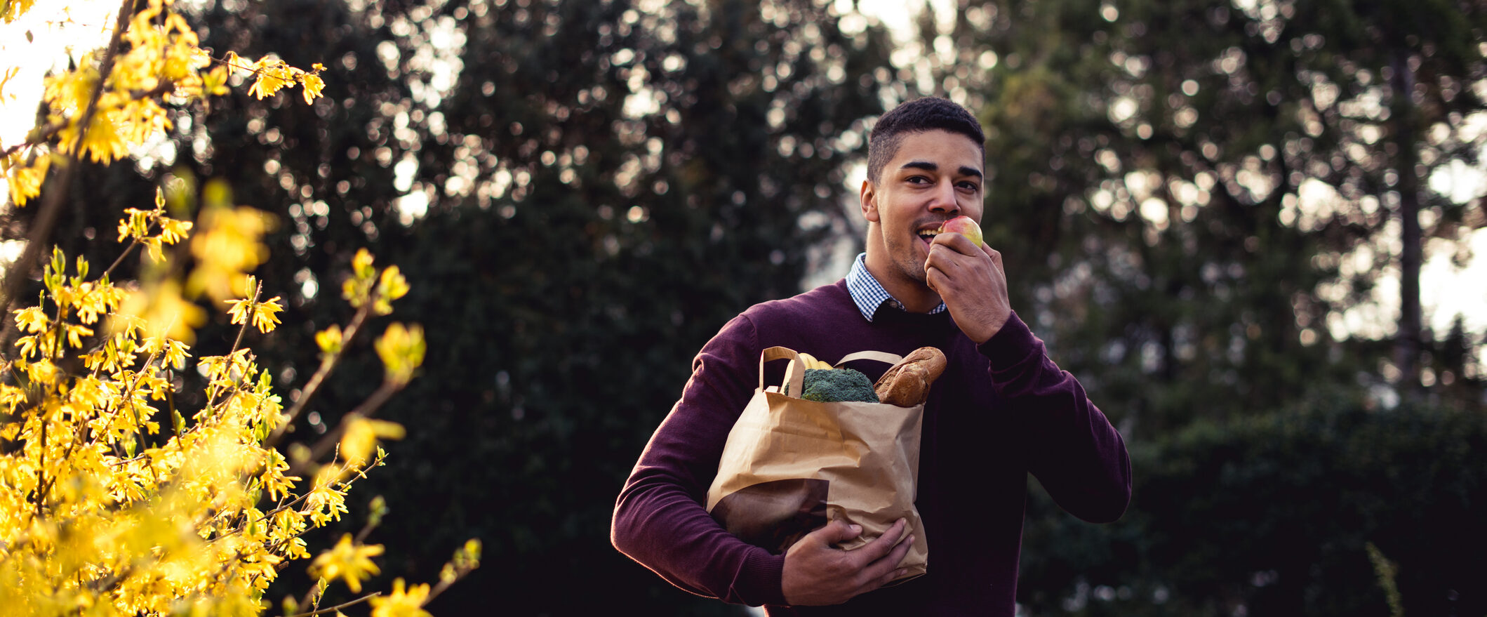 Man eating an apple while walking in a park. Photo by iStock, Georgijevic.