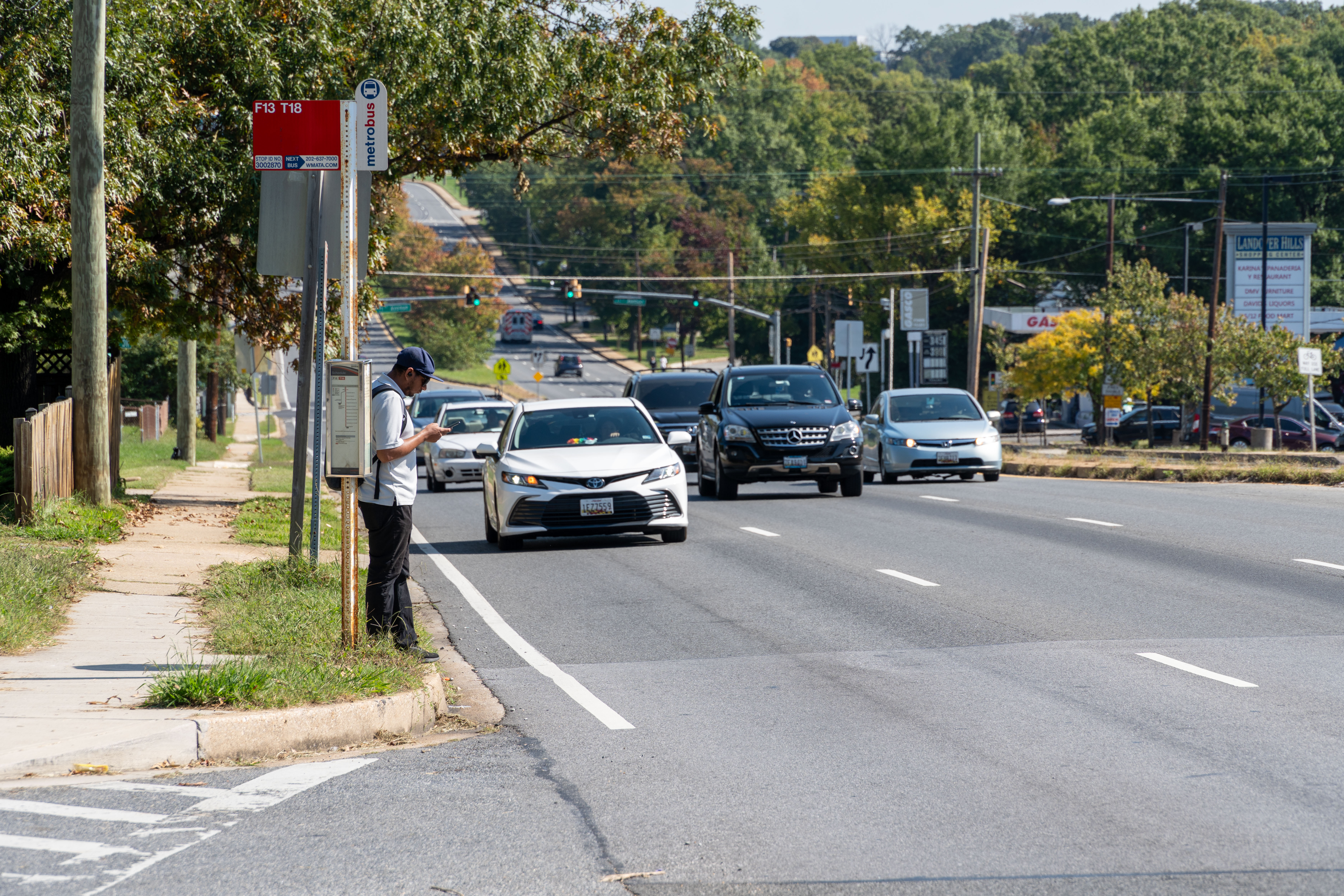 Man waits for bus next to busy road.