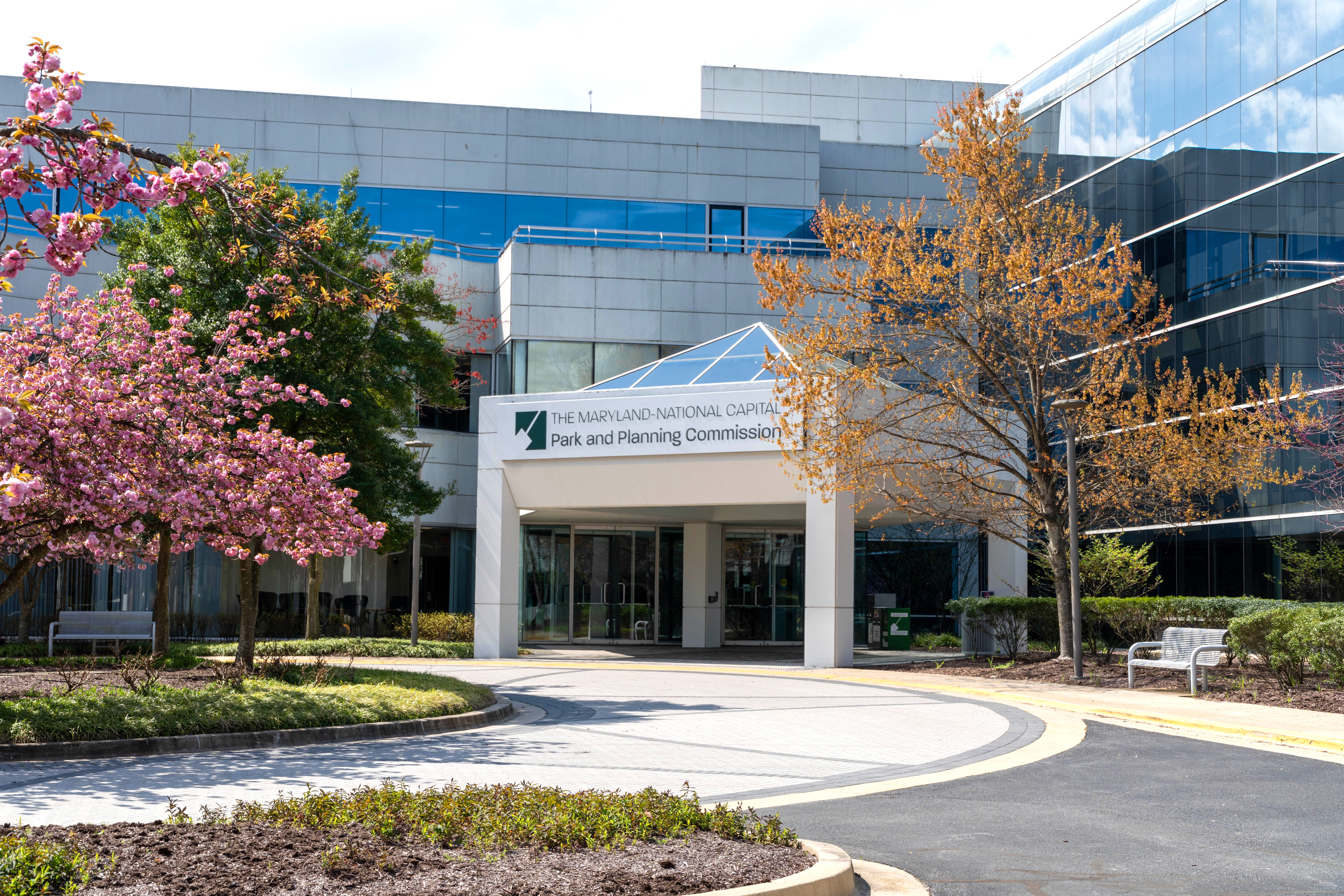 Front entrance to the M-NCPPC Largo Headquarters building, surrounded by flowering trees.