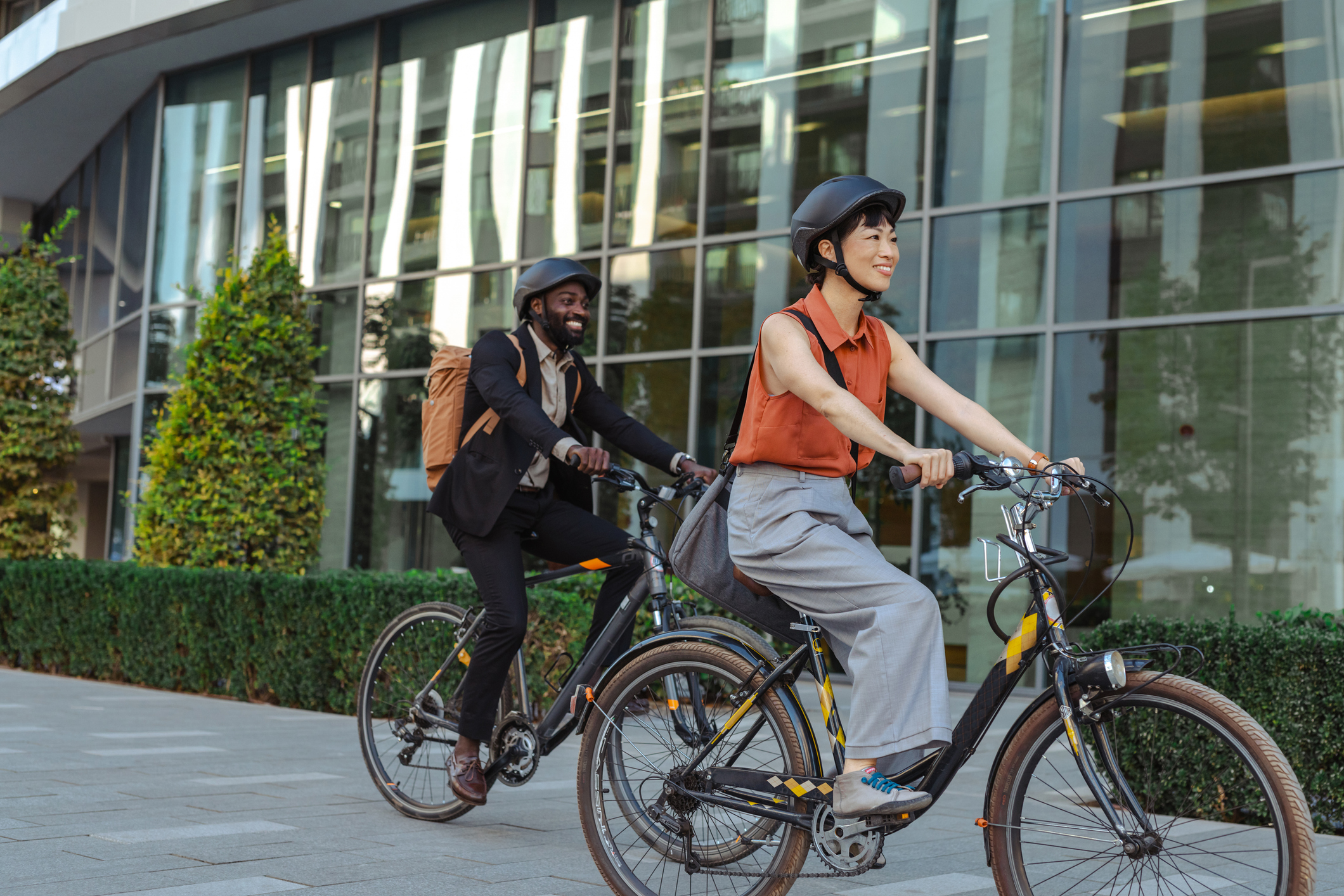 Two colleagues with helmets bike to work on a sunny morning, showcasing sustainable commuting and healthy lifestyle choices. Photo by blackCAT, istockphoto.com
