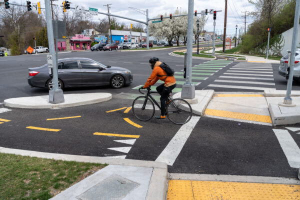 Man on bicycle at busy intersection waiting for light to change.