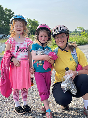 Two young girls and their mother dressed in bright colors, wearing bike helmets, partake in the Bike to Word Day pitstop in Prince George's County, Maryland.