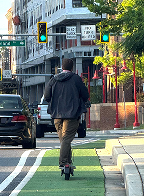 Man on scooter rides in bike lane along US 1 in College Park, Maryland.