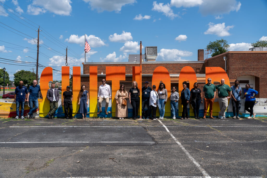Cultural arts tour participants pose in front of a large, colorful Suitland sign.