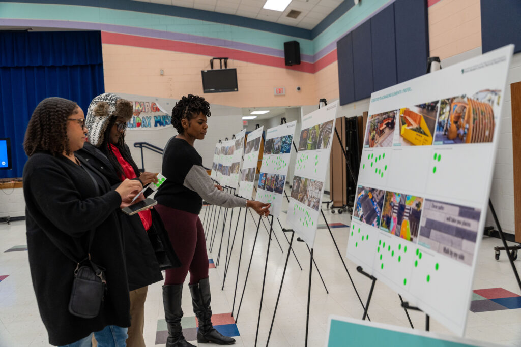 Participants review cultural arts display boards and mark preferences with green stickers at a Suitland planning meeting.