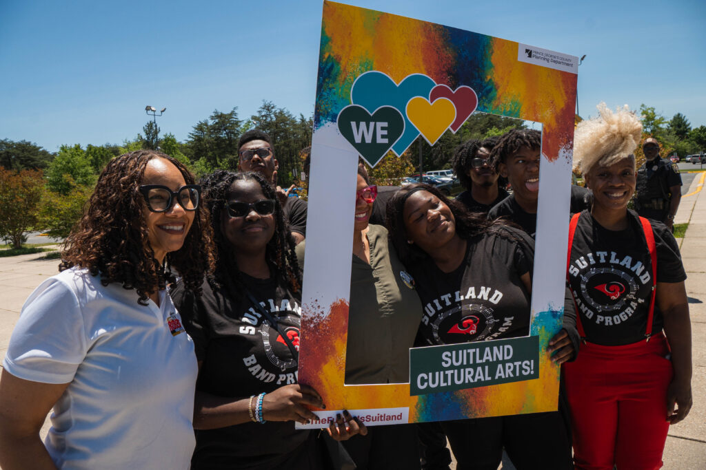 Attendees pose with a colorful “Suitland Cultural Arts!” photo frame at the Future Is Suitland celebration.